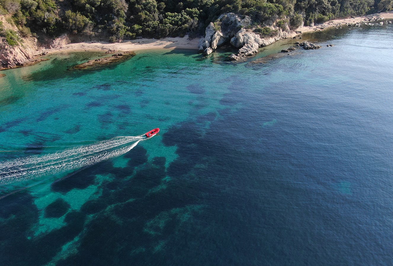 Bateau sans permis Marinaloc naviguant dans une crique turquoise près de Propriano, Corse-du-Sud